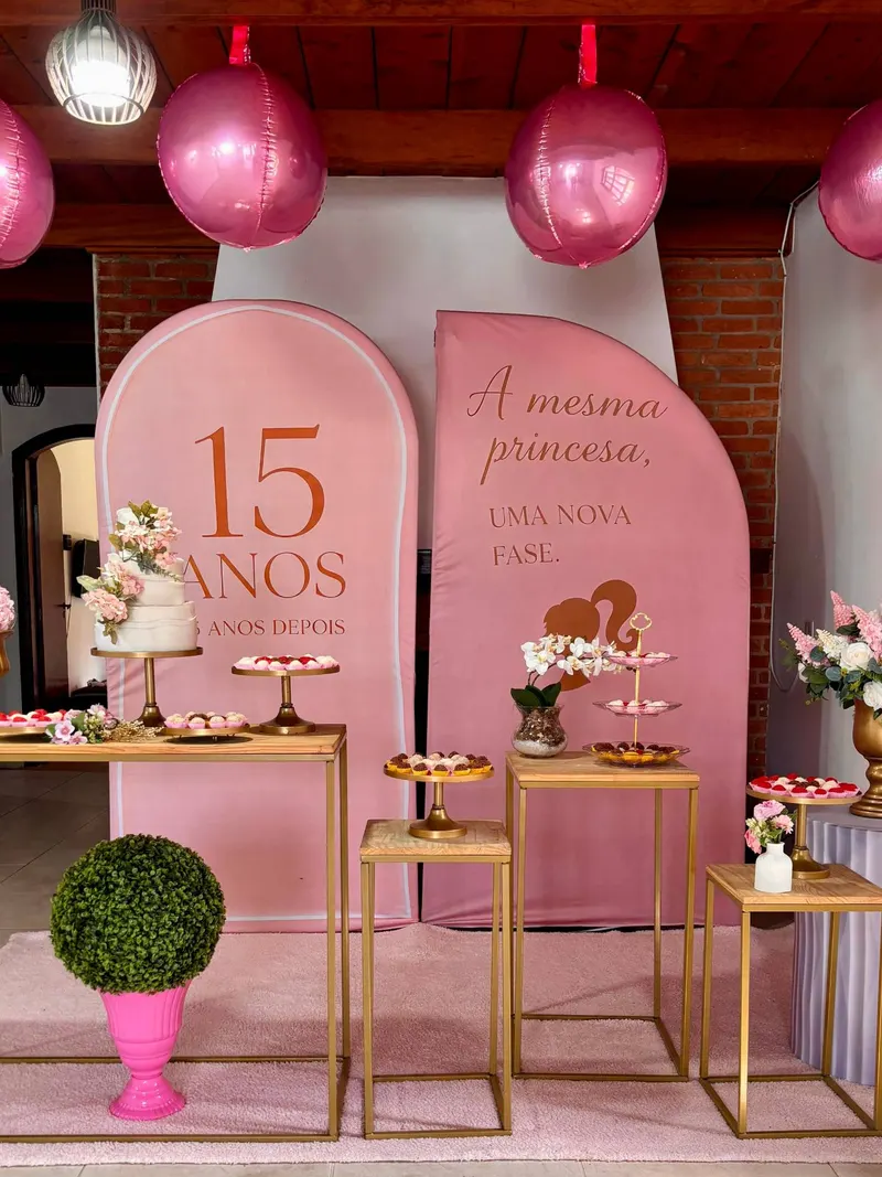 Painéis rosa com “15 anos… 25 anos depois” e “a mesma princesa, uma nova fase”, mesa do bolo e balões
