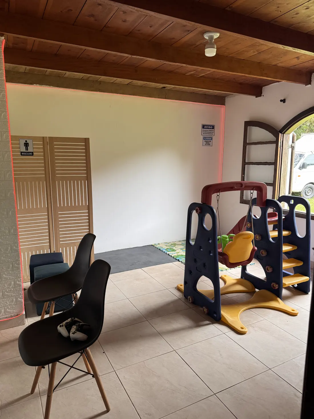 Sala de brinquedos com escorregador e balanço infantil e cadeiras para os adultos